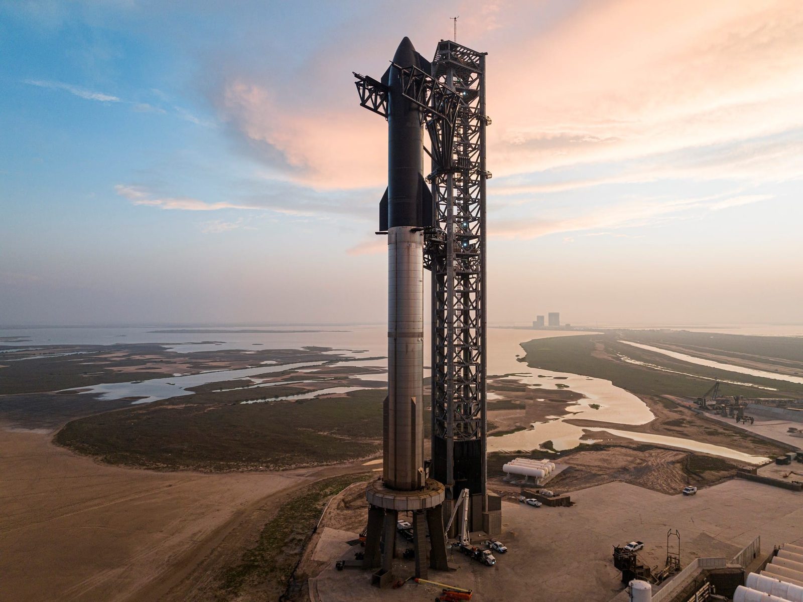 El cohete Starship montado sobre su torre de lanzamiento, frente a una costa al atardecer