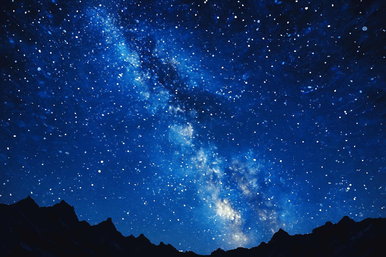 Vía Láctea sobre un cielo azul lleno de estrellas y la silueta de unas montañas