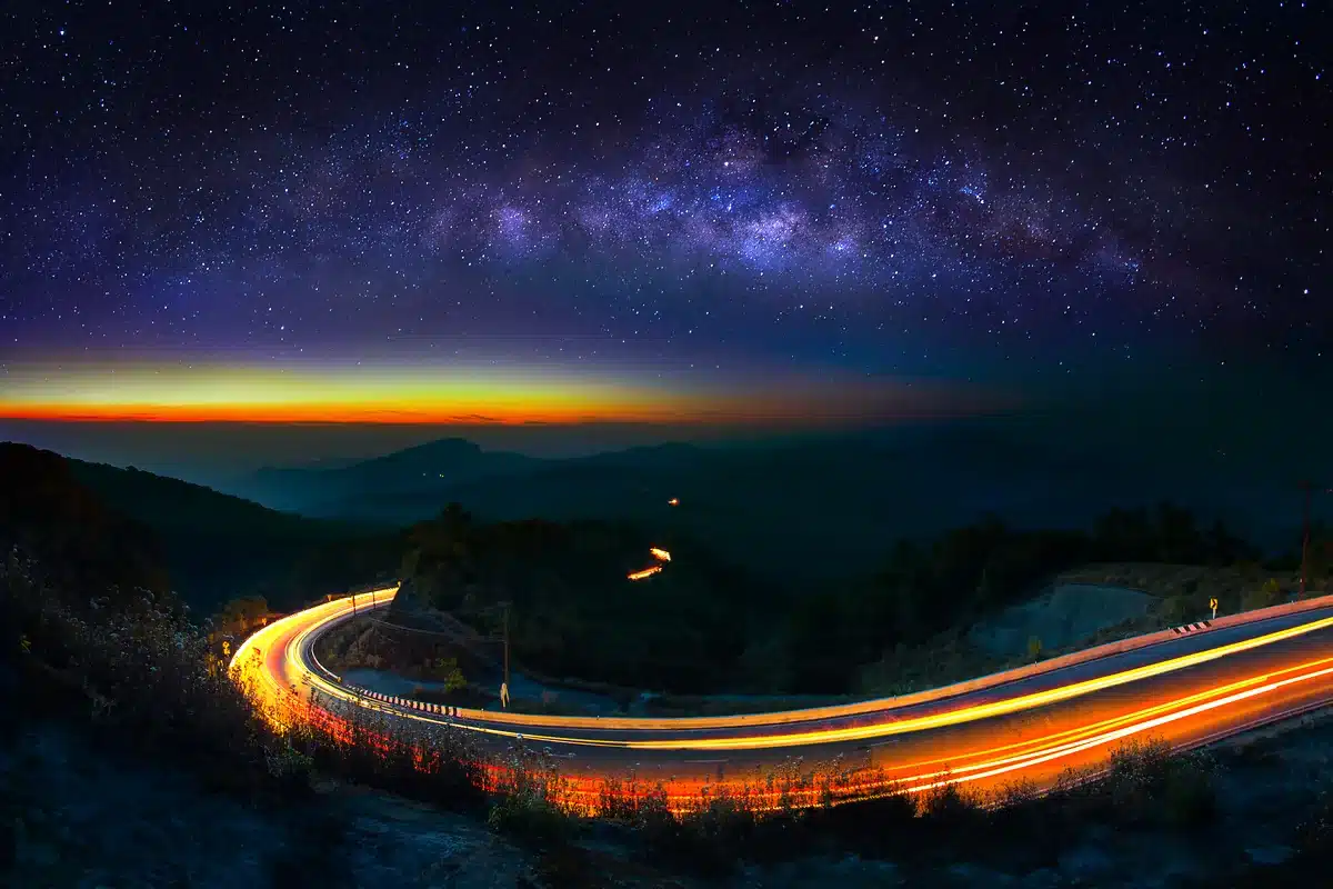 Vía Láctea sobre una carretera de montaña con estelas de luz de autos