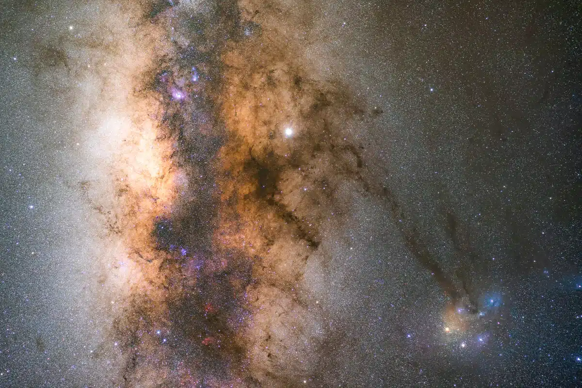 Región de la Vía Láctea con nubes de polvo oscuro y estrellas de colores