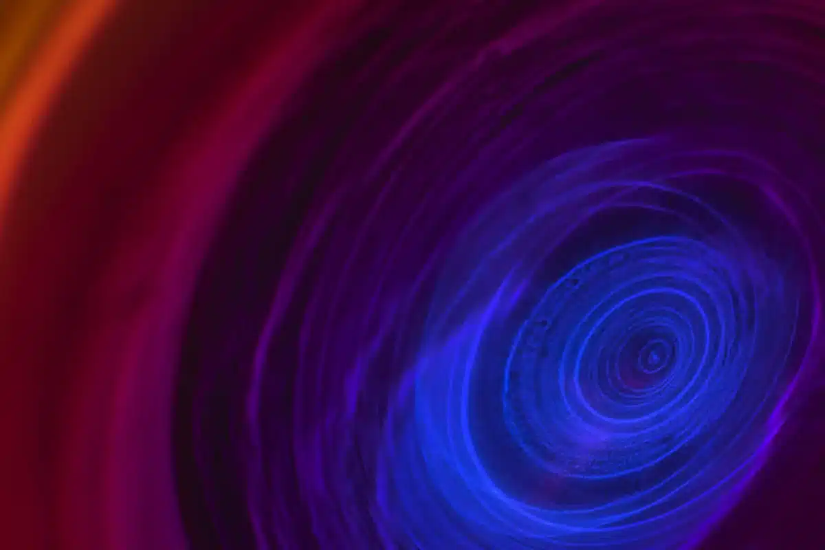 Espirales de luz azul y violeta que giran hacia un centro sobre un fondo rojizo