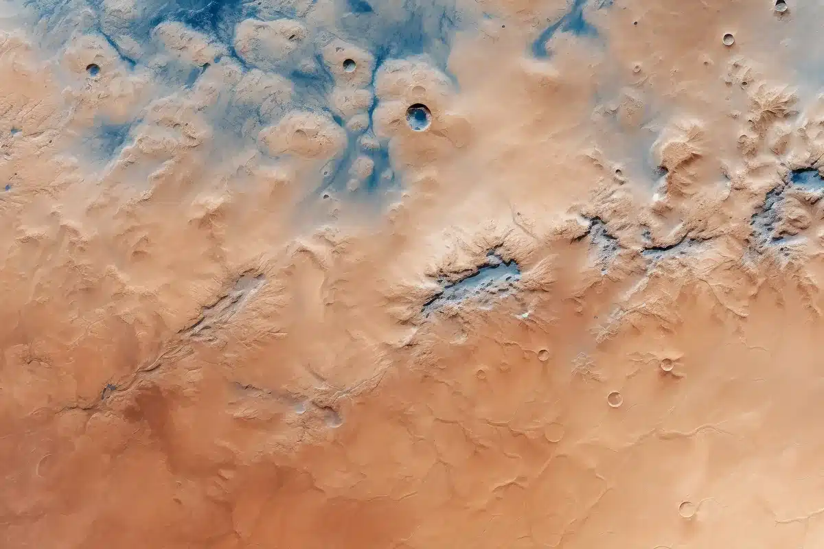 Vista aérea de un terreno ocre con cráteres pequeños y zonas azuladas