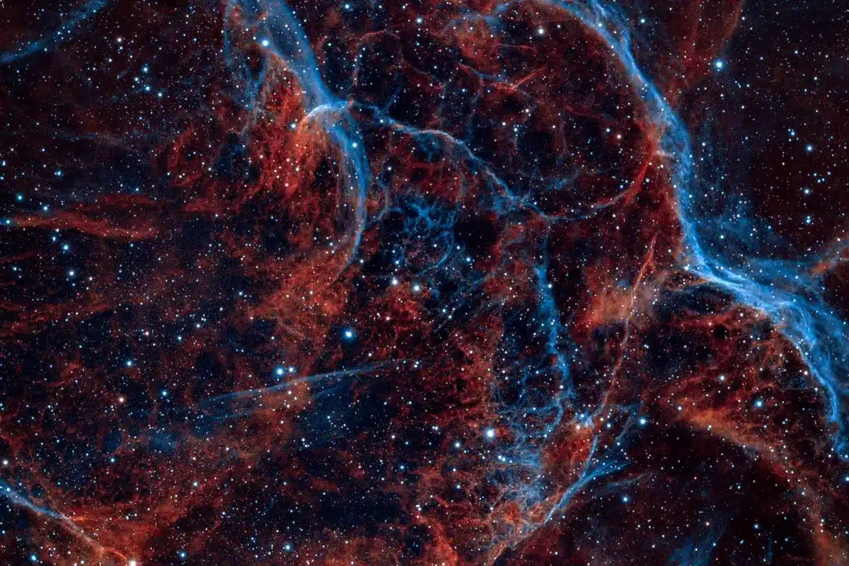 Filamentos de gas rojo y azul de una nebulosa entre estrellas