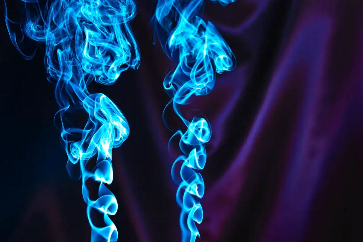 Volutas de humo azul sobre un fondo violeta oscuro
