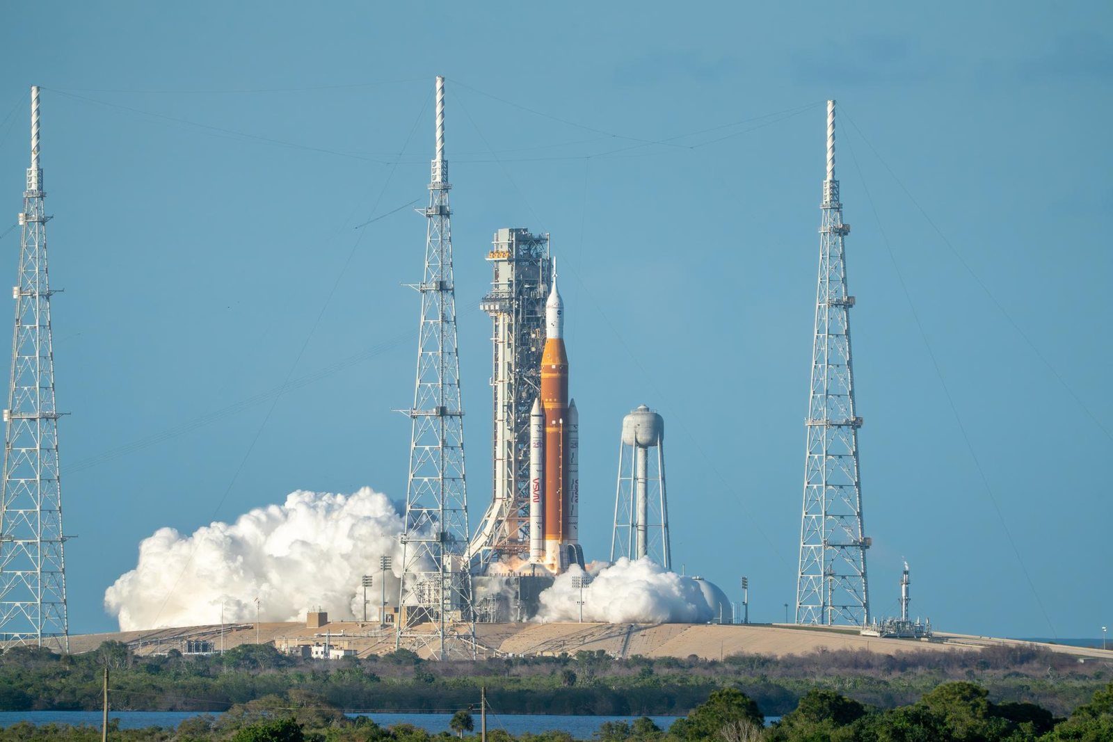 El cohete SLS de la misión Artemis II despega del Complejo 39B del Centro Espacial Kennedy entre torres de pararrayos