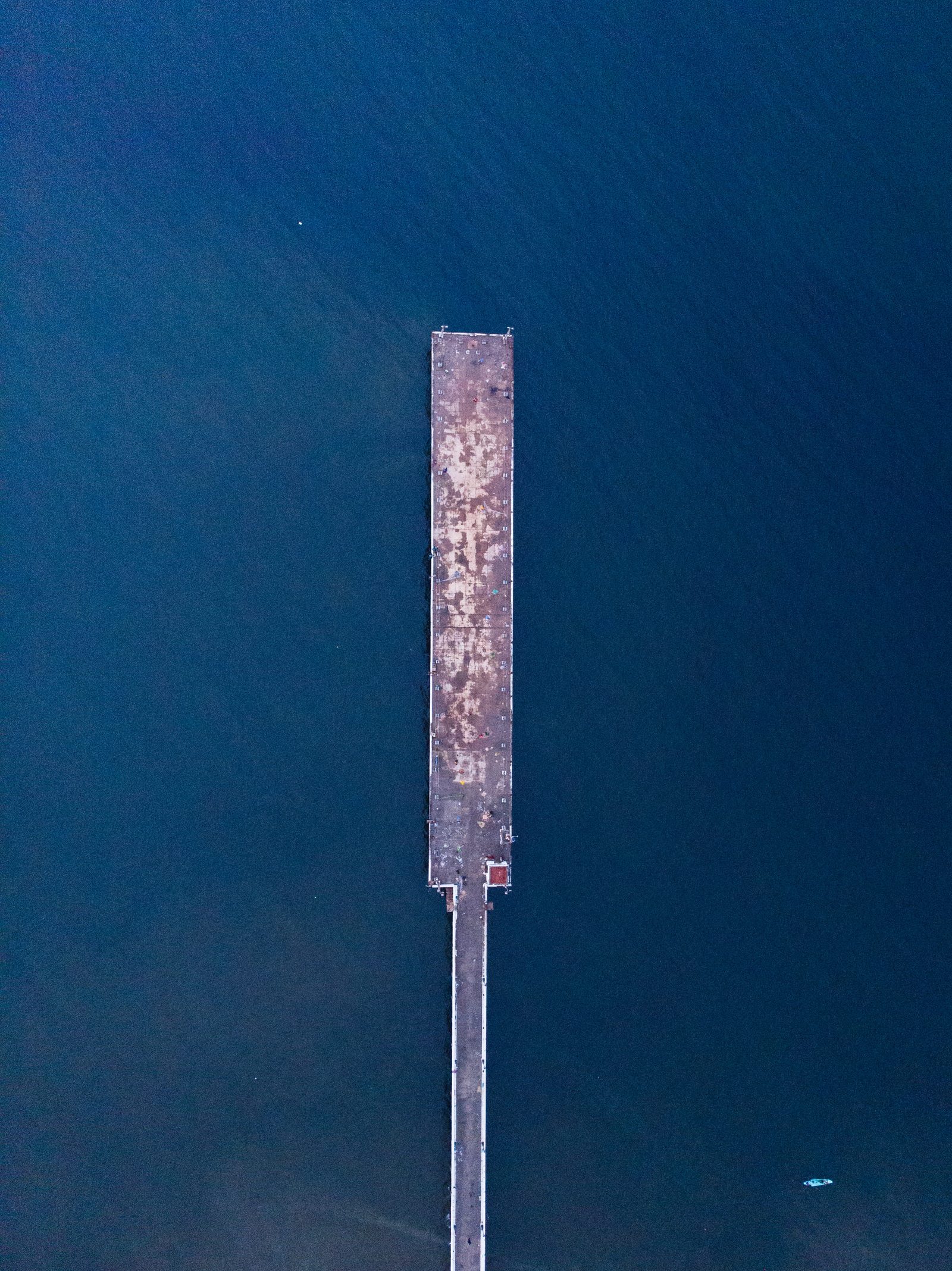 Vista aérea de una estructura alargada de metal oxidado en medio de agua azul oscura