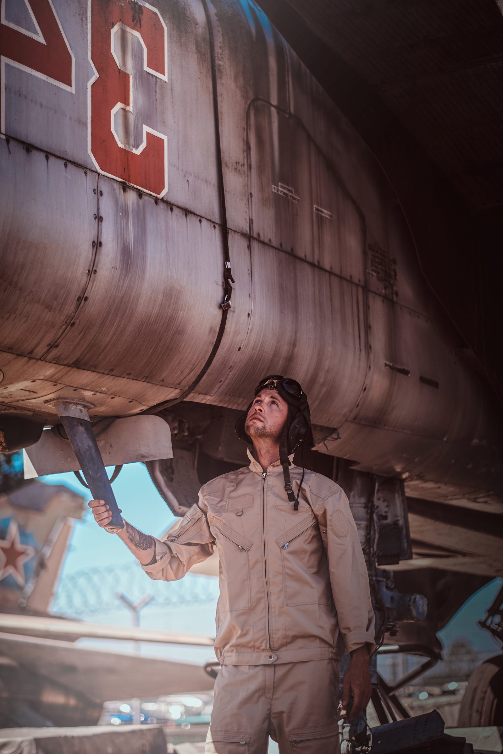 Hombre con casco de aviador debajo del fuselaje de un avión antiguo